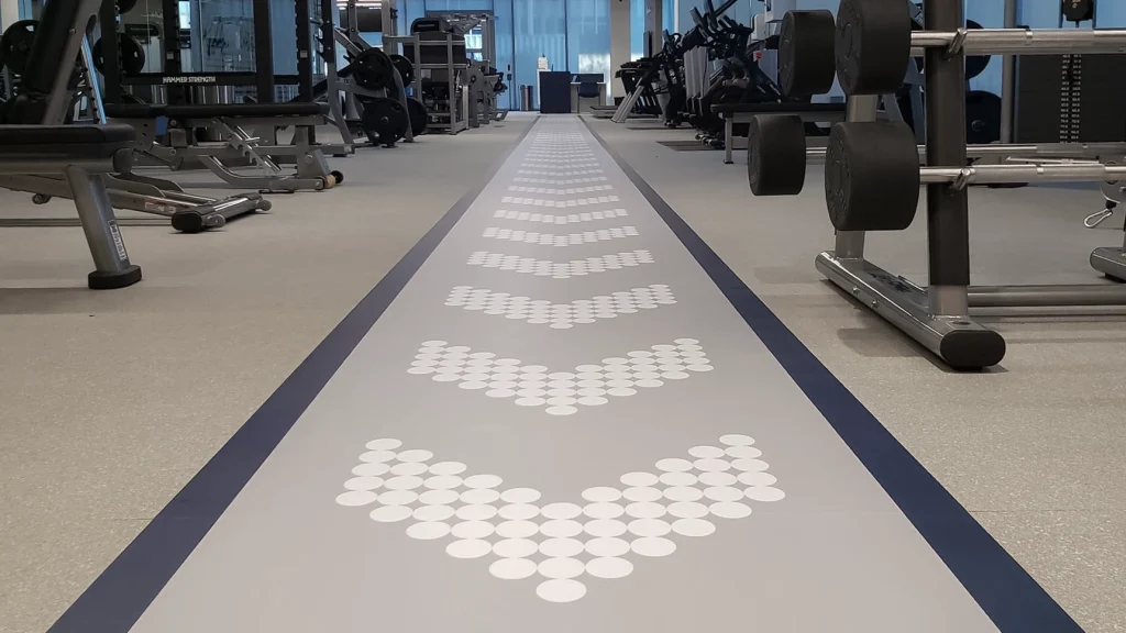 Engineered floor graphic with chevron-style circular shapes directing foot traffic inside a fitness facility