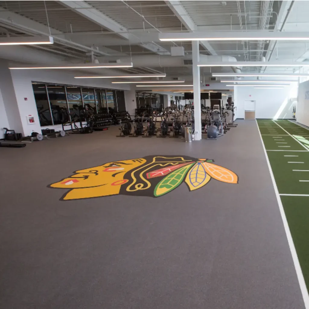 Wide view of a fitness facility featuring a large engineered Chicago Blackhawks Native American logo installed at the center of the space.
